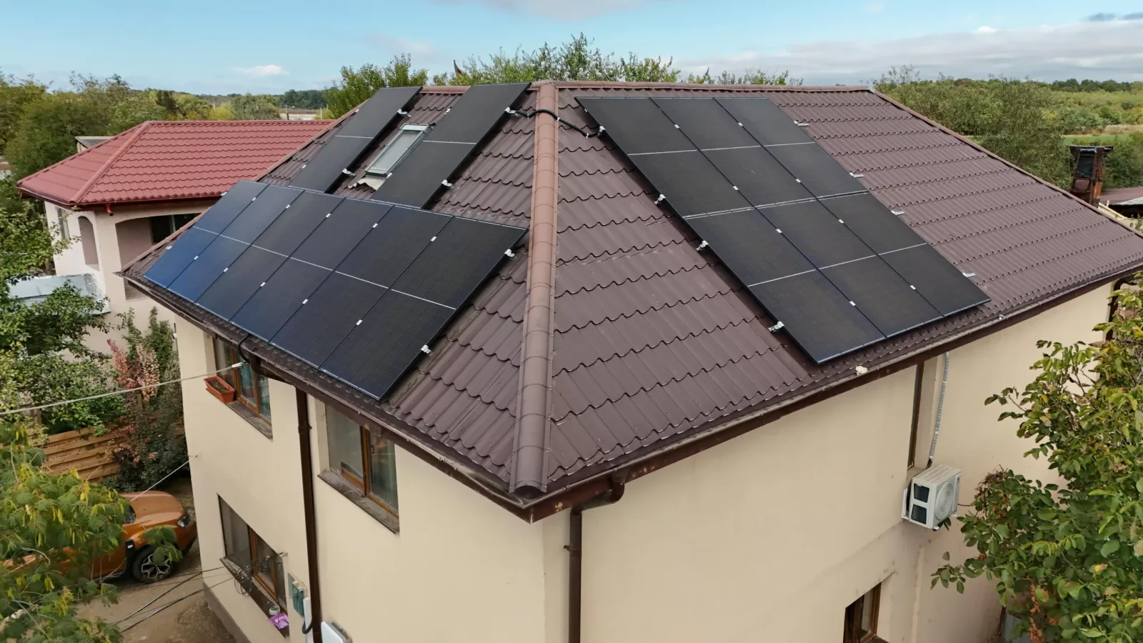 Casă cu panouri fotovoltaice pe două ape ale acoperișului, văzută din dronă