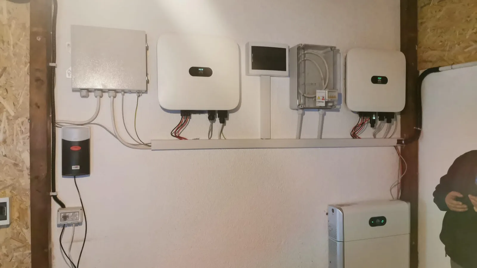 Două invertoare Huawei, un modul de back-up și o baterie LUNA2000 montate pe un perete alb