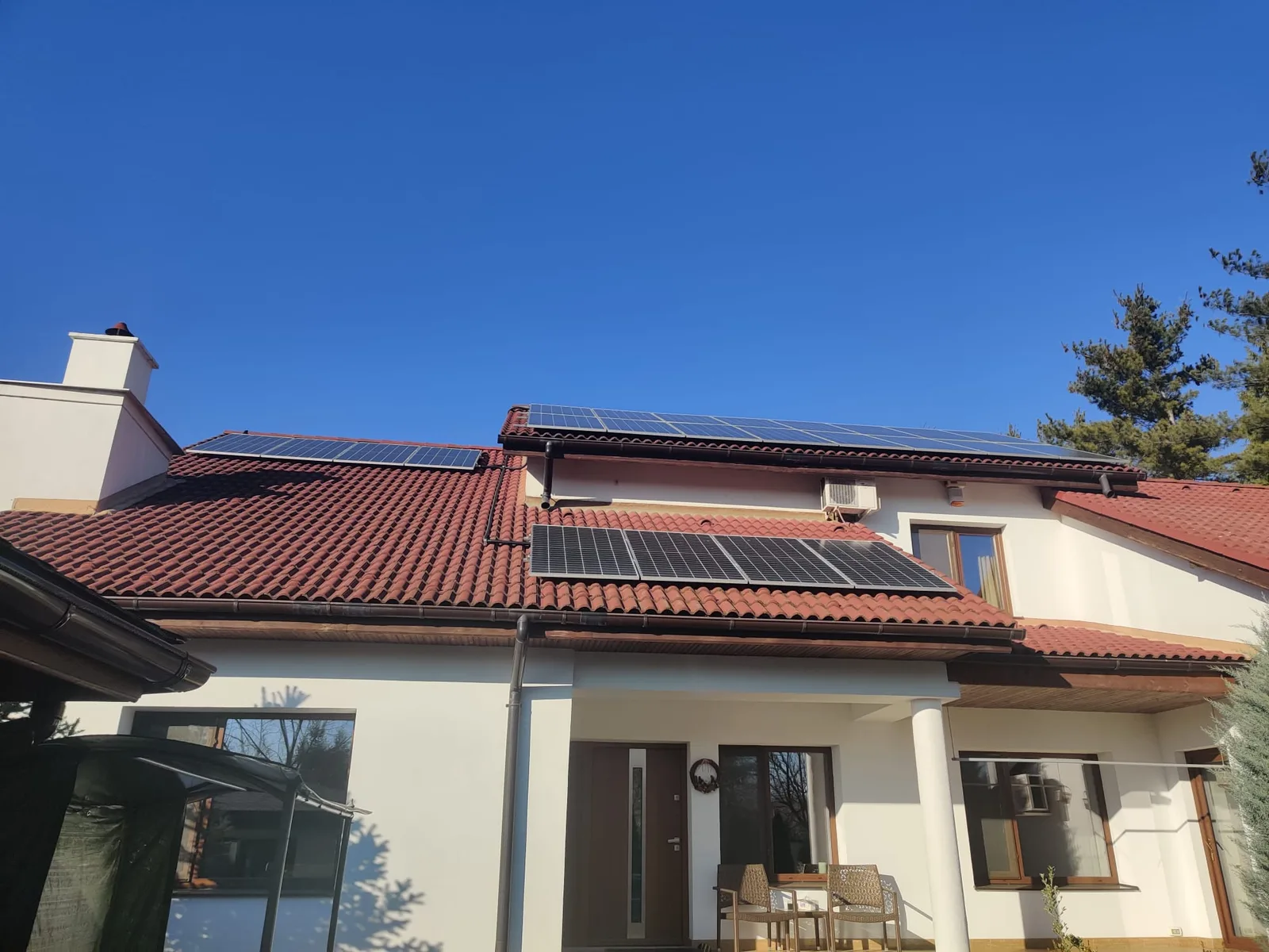 Casă cu panouri fotovoltaice pe acoperișul de țiglă, sub un cer senin