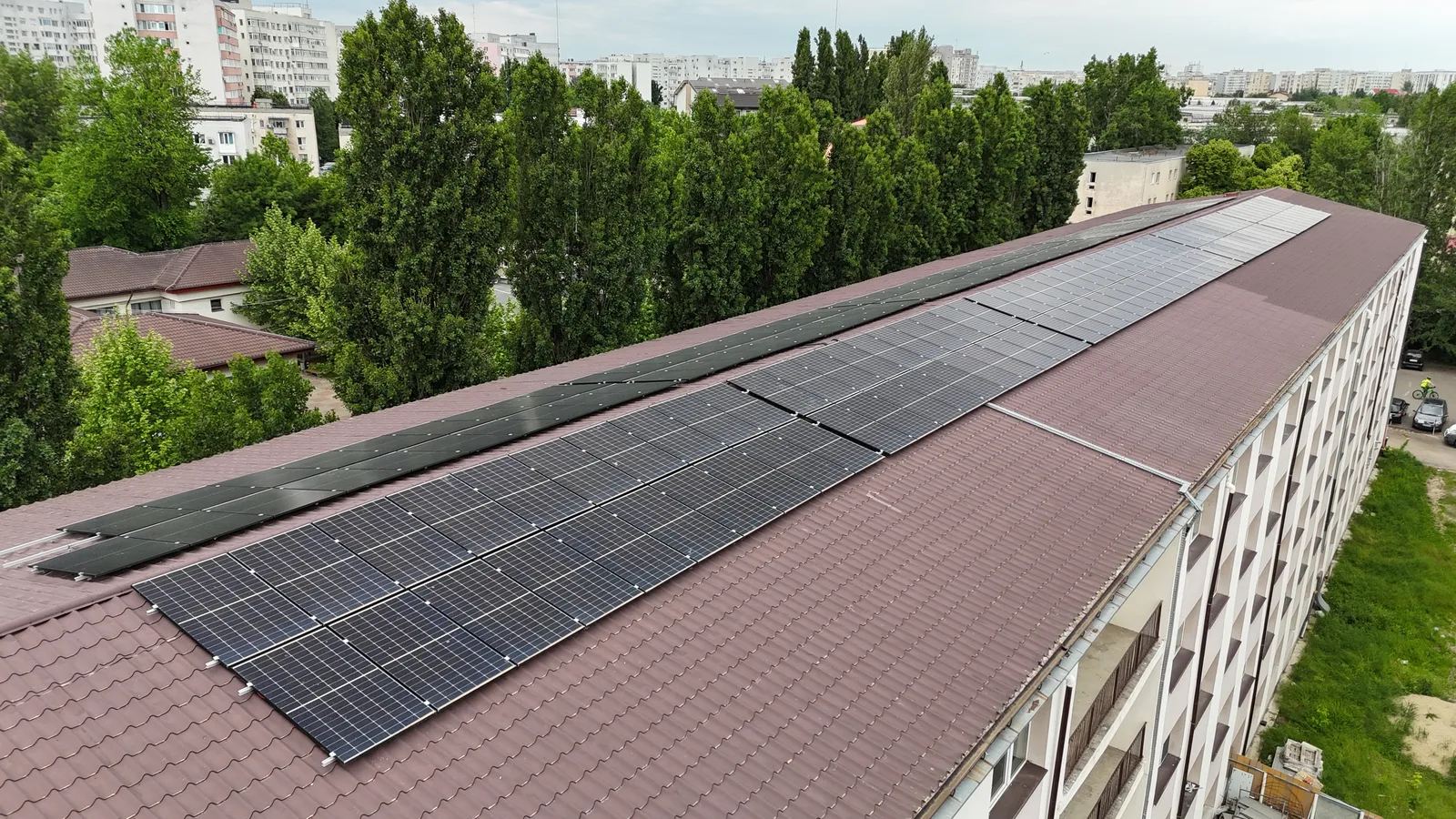 Clădire lungă cu panouri fotovoltaice pe toată coama acoperișului, văzută din dronă